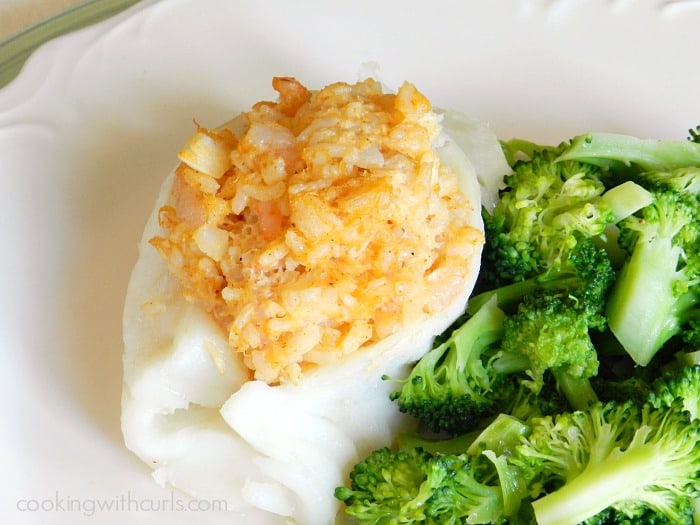 shrimp and crab stuffed cod on a white plate beside steamed broccoli
