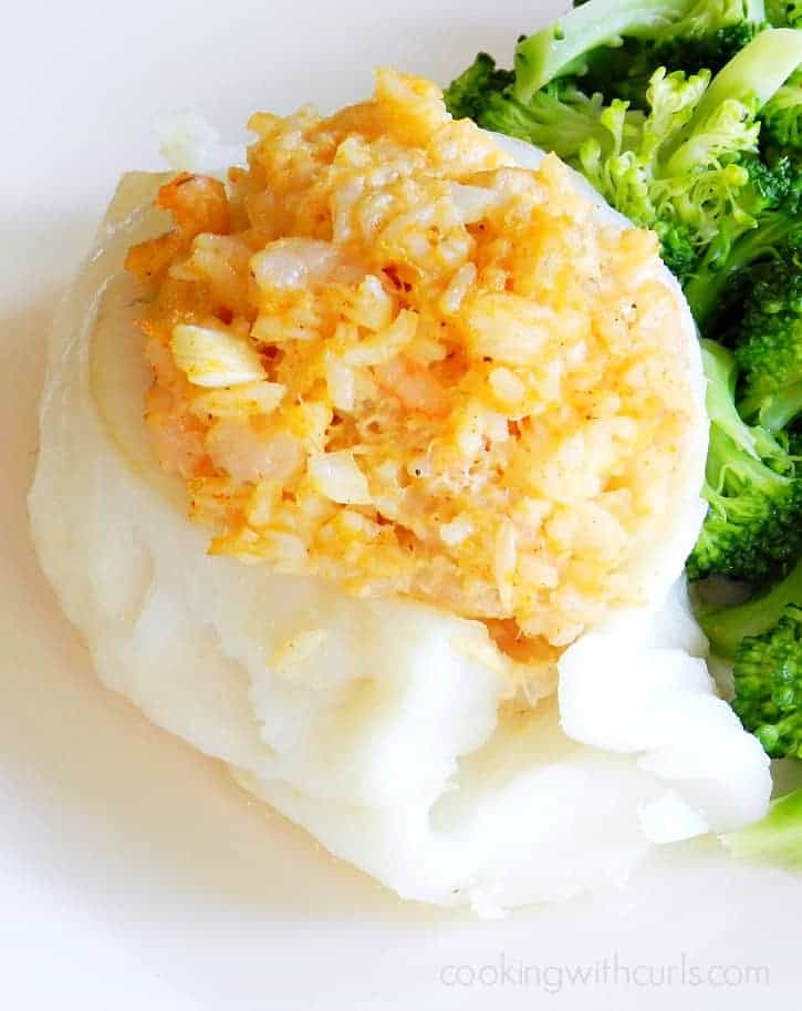 cod stuffed with shrimp and crab set on a white plate with steamed broccoli
