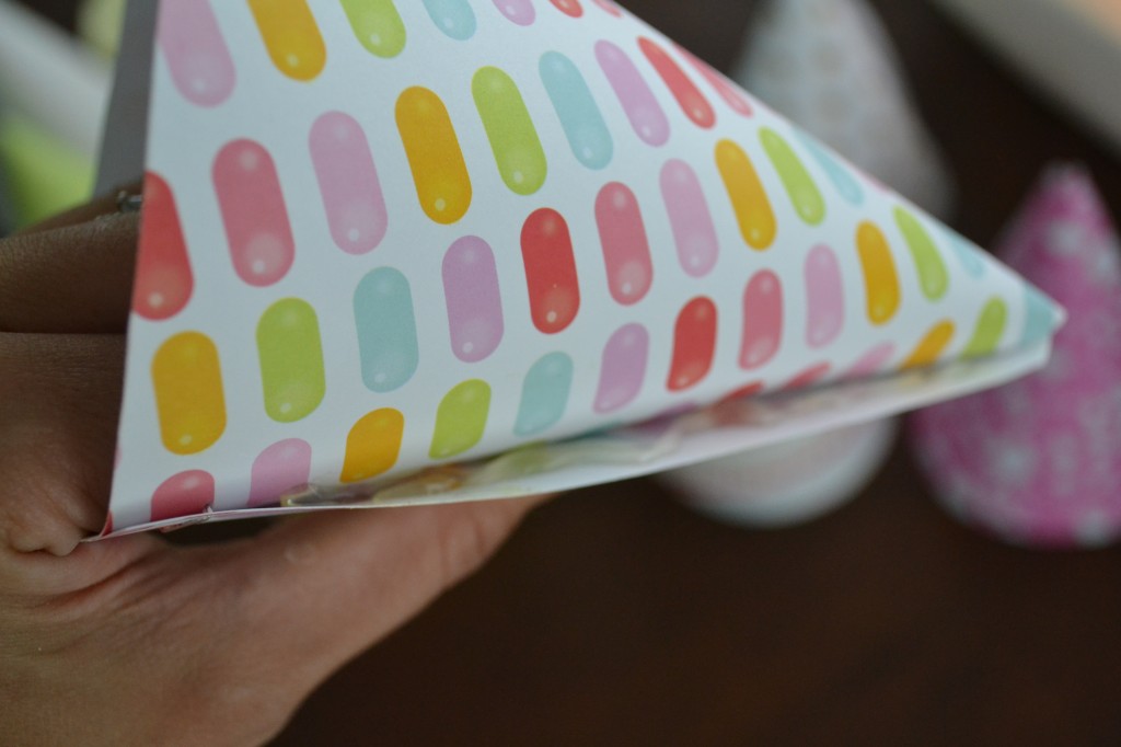 Once the scrapbook paper is cut, roll it into a cone-shaped hat. 