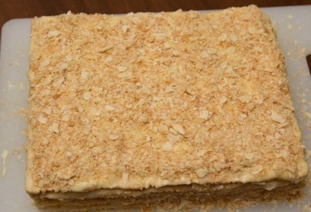 готовый торт наполеон из слоеных коржей на белом подное на столе