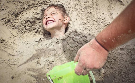 семейная фотсоессия на море девочка закопанная в песок